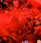 people in blue shirts with red powder on their hands